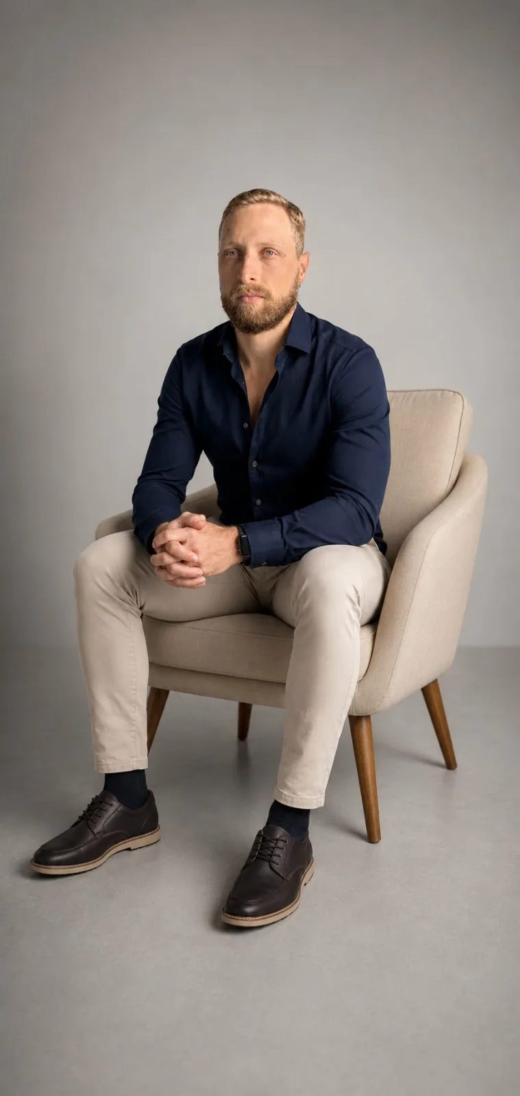 Osmar Gusso Neto, consultor financeiro, sentado em poltrona em retrato profissional com camisa azul-marinho
